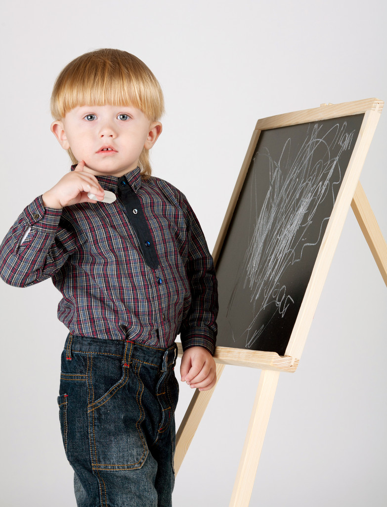 маленький хлопчик малює крейдою щось на дошці
 - Фото, зображення