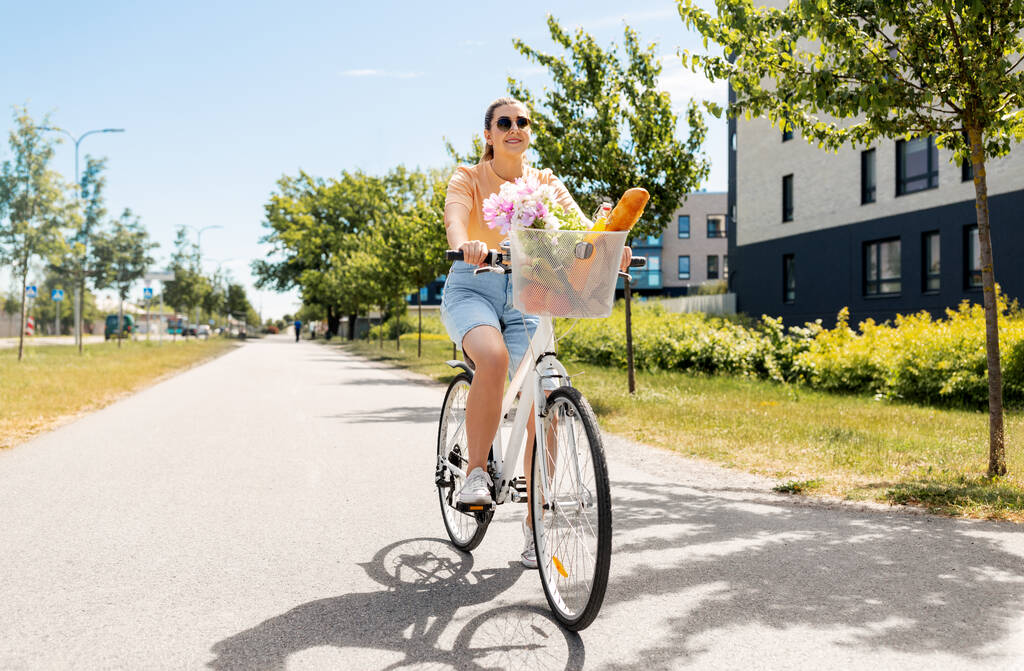 woman with food and flowers in bicycle basket - Photo, Image