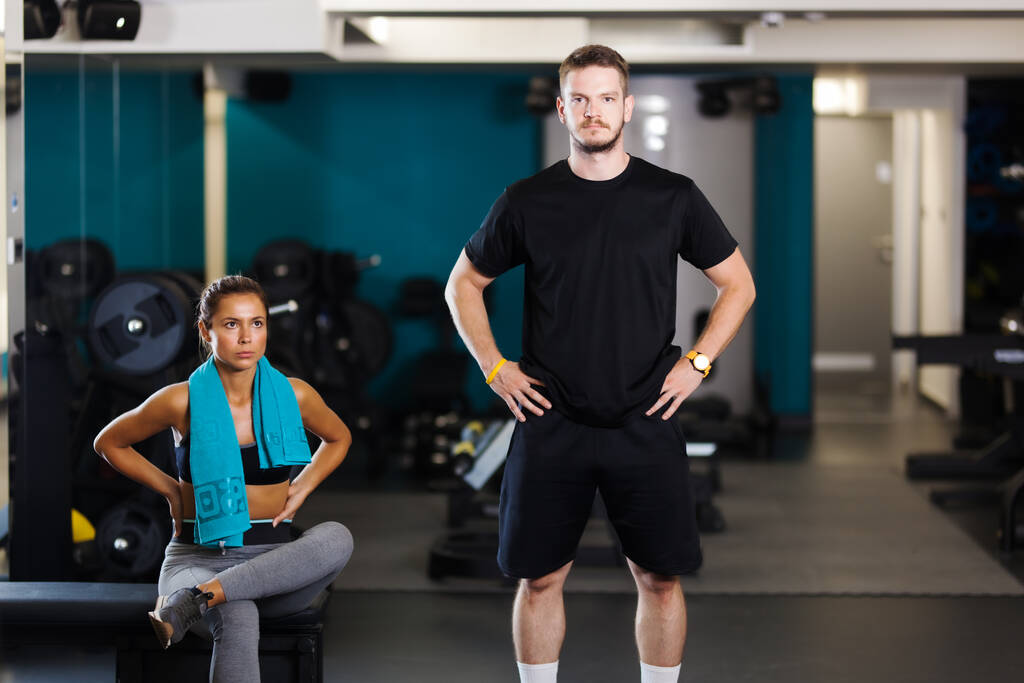 Instructor de fitness con una clienta. Preciosa pareja posando en un gimnasio. - Foto, imagen