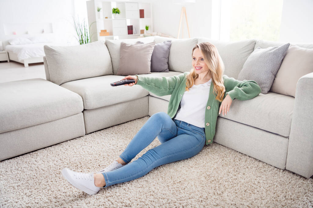 Portret atrakcyjnej wesołej, falistej dziewczyny siedzącej na podłodze odpoczywającej w wolnym czasie oglądając serię seriali w domu światło białe mieszkanie w pomieszczeniu - Zdjęcie, obraz