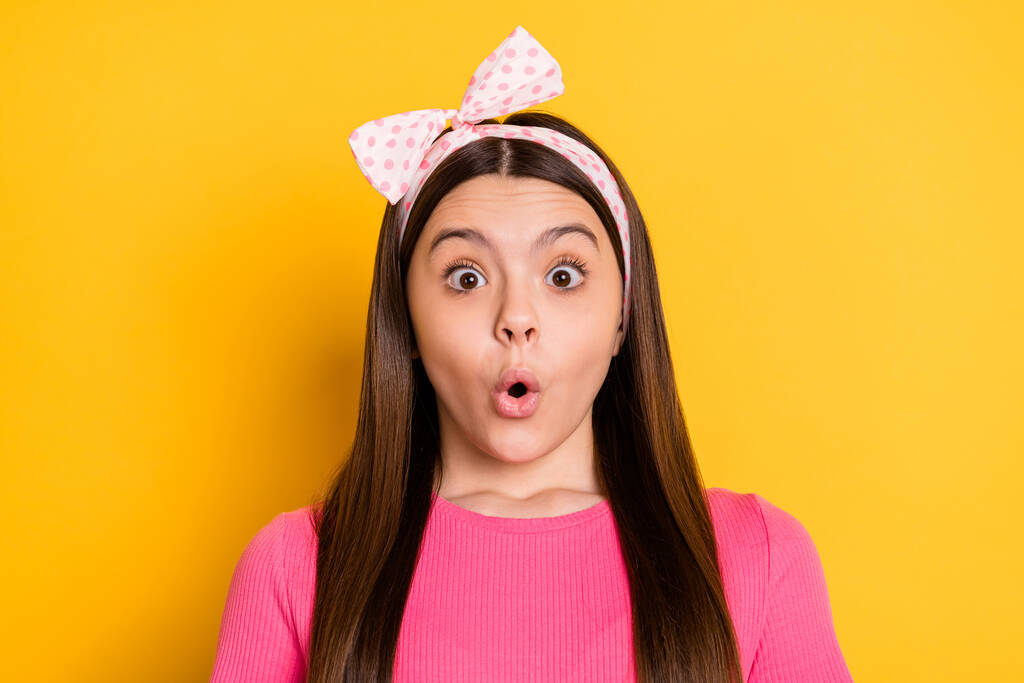 Φωτογραφία από γοητευτικό εντυπωσιασμένο κορίτσι σχολείο φορούν ροζ t-shirt μεγάλα μάτια απομονωμένο κίτρινο χρώμα φόντο - Φωτογραφία, εικόνα