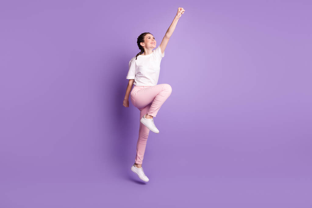 Pleine taille profil photo de côté de jeune fille attrayante heureux sourire positif saut super héros isolé sur fond de couleur violette - Photo, image