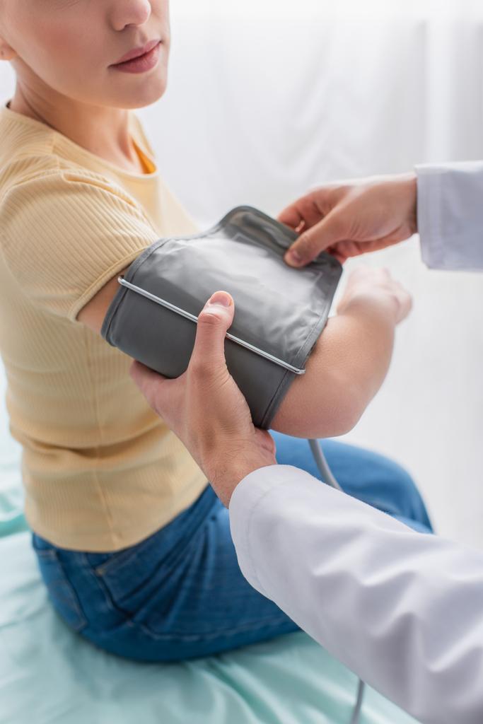 osittainen näkymä lääkäriin, joka laittaa rannekkeen tonometriä potilaan käsivarteen - Valokuva, kuva