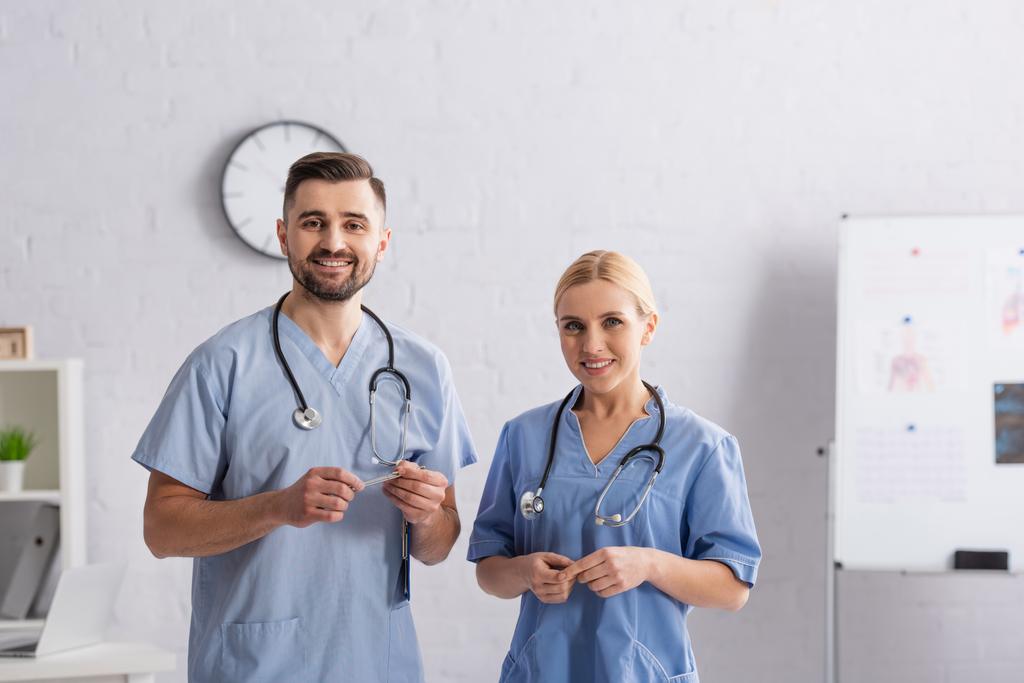 Lächelnde Ärzte in blauer Uniform lächeln in die Kamera im Krankenhaus - Foto, Bild