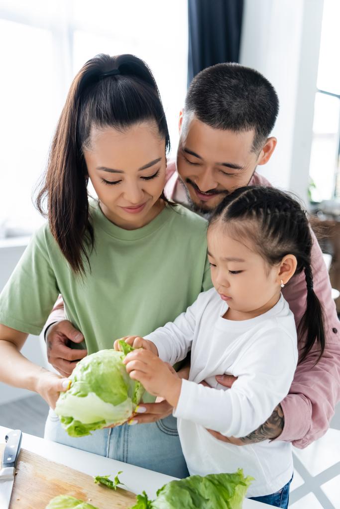 幸せなアジア系の家族がキッチンで新鮮なレタスを見て  - 写真・画像