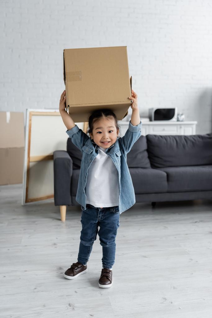 happy asian toddler girl holding carton box in new home - Photo, Image