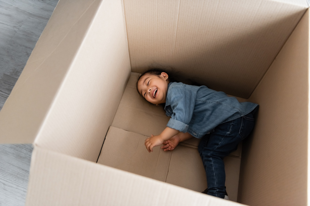 vue grand angle de heureux asiatique tout-petit fille couché dans la boîte en carton vide  - Photo, image