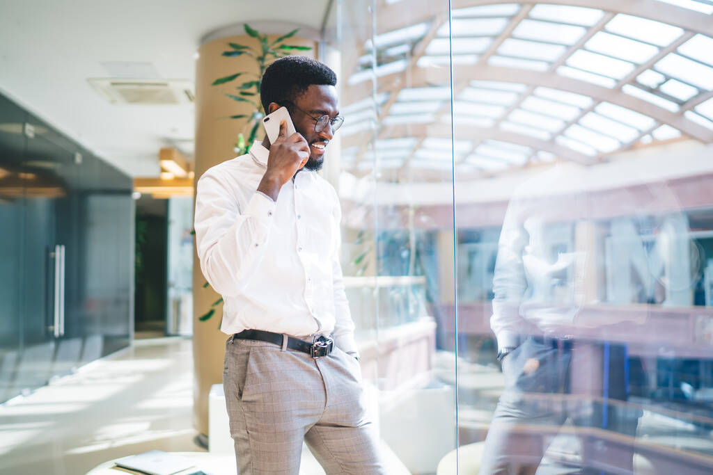 Afrikai amerikai férfi okos alkalmi viselet és optikai szemüveg, hogy a szem védelme élvezi a mobiltelefon beszélgetés során munkahelyi szünet az irodában, sikeres férfi telefonálás mobiltechnológiával - Fotó, kép