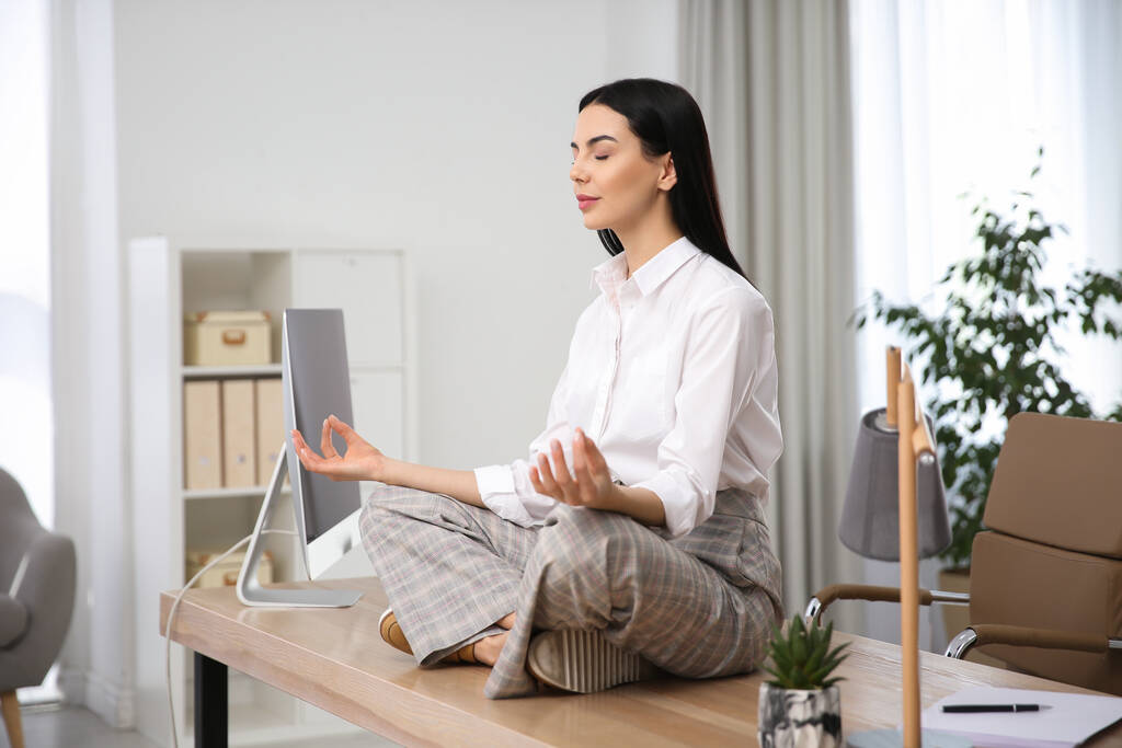 職場で瞑想する若い女性。ストレス解消運動 - 写真・画像