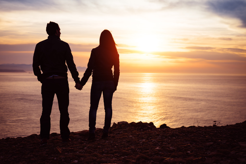 Amantes mirando puesta de sol sobre el mar
 - Foto, Imagen