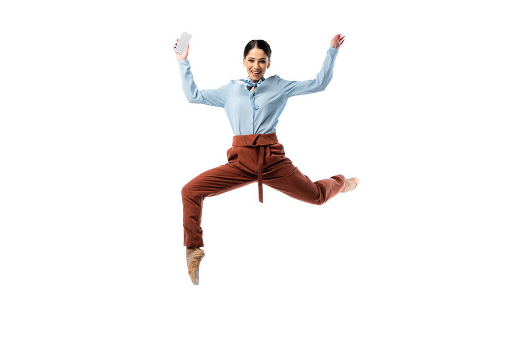 Bailarina positiva saltando con smartphone aislado en blanco  - Foto, Imagen