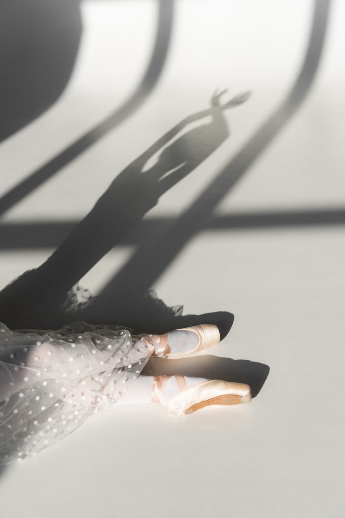 Oříznutý pohled na baletku sedící na šedém pozadí  - Fotografie, Obrázek