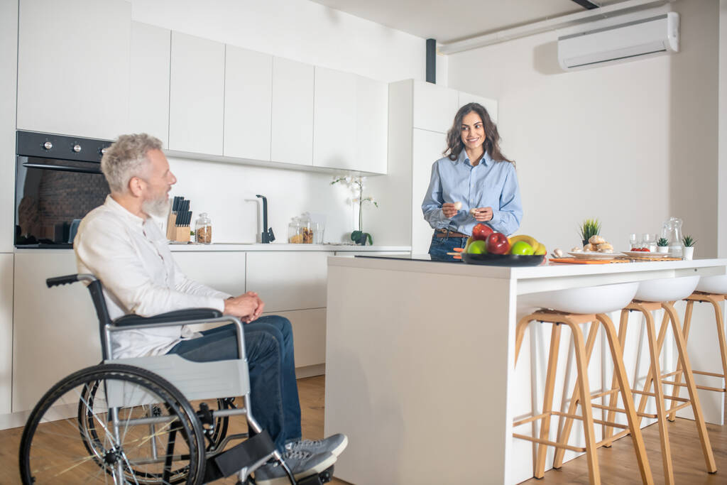 Γκρι μαλλιά ανάπηρος άντρας και η γυναίκα του στο σπίτι πριν από το πρωινό - Φωτογραφία, εικόνα