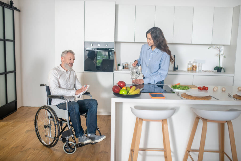 Hombre discapacitado de pelo gris y su esposa en casa antes del desayuno - Foto, imagen