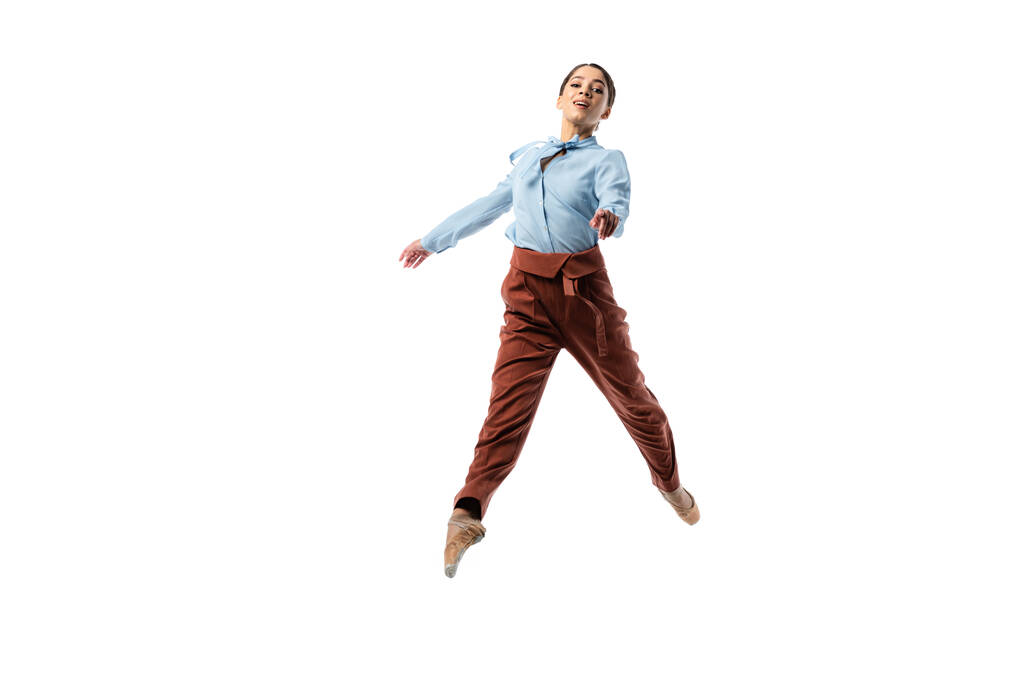 Улыбающаяся балерина смотрит в камеру, прыгая изолированной на белом  - Фото, изображение