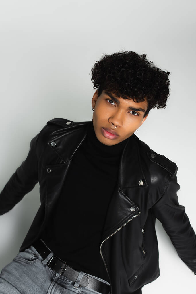 overhead view of african american man in black leather jacket looking at camera on grey  - Foto, Imagen