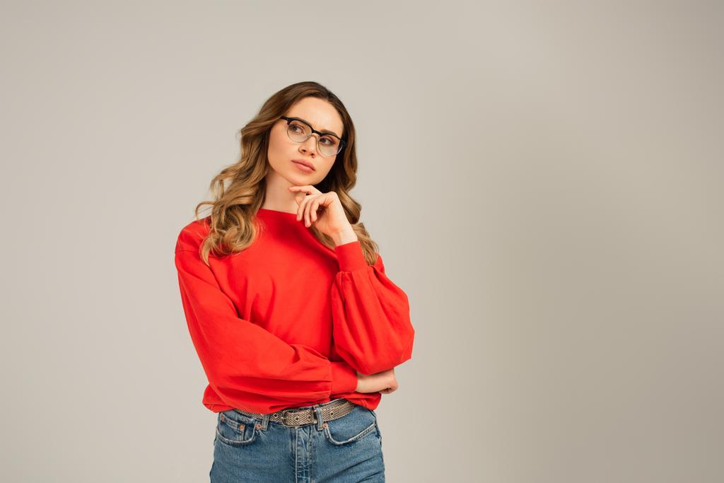 Nachdenkliche Frau mit Brille blickt vereinzelt auf grau - Foto, Bild