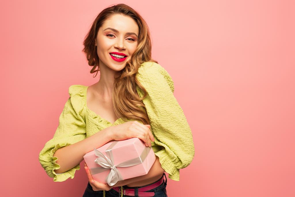 elégedett nő gazdaság csomagolt ajándék doboz elszigetelt rózsaszín  - Fotó, kép