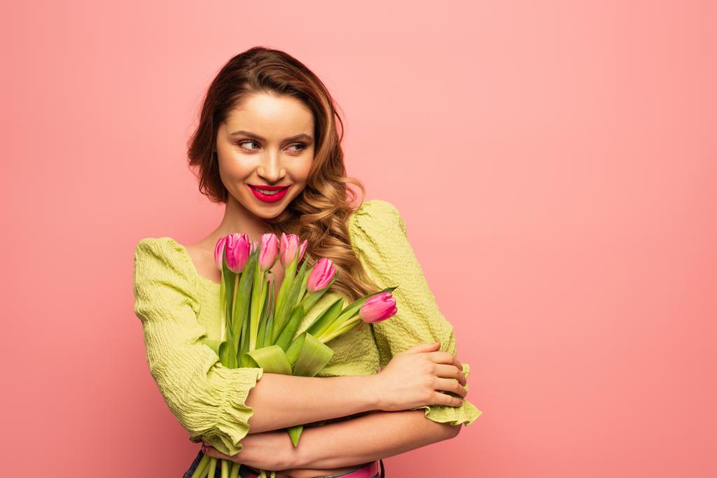 mujer alegre sosteniendo ramo de tulipanes aislados en rosa - Foto, Imagen