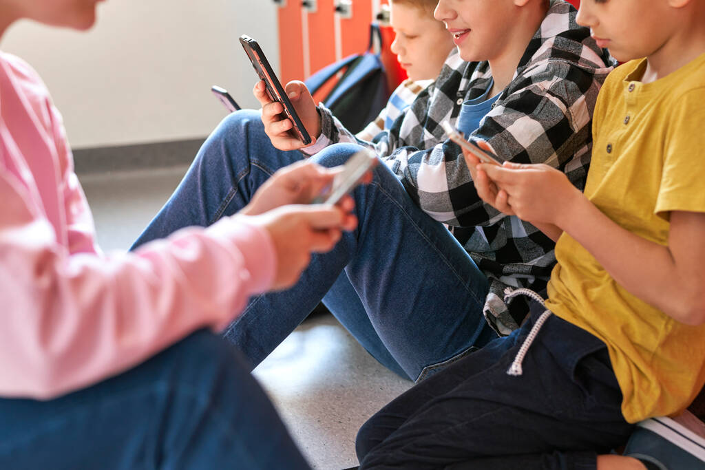 Κοντινό πλάνο έφηβοι γραπτών μηνυμάτων στο κινητό τηλέφωνο στο διάδρομο του σχολείου - Φωτογραφία, εικόνα