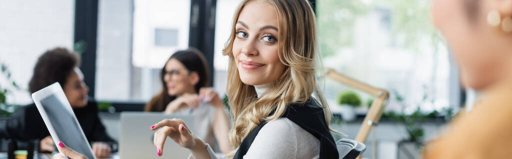 femme d'affaires souriante pointant vers tablette numérique avec écran blanc près de collègues flous, bannière - Photo, image