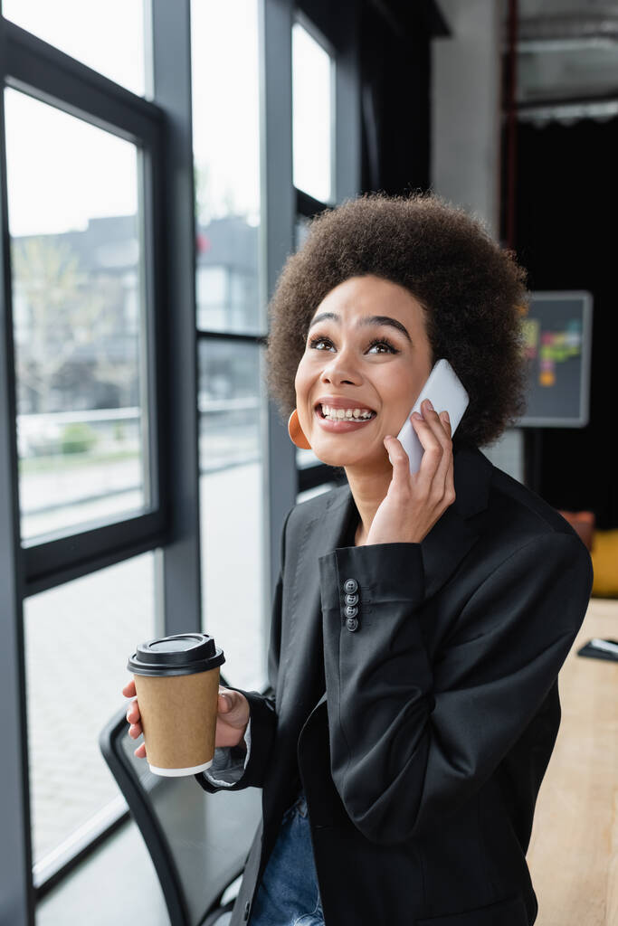 vzrušený africký americký podnikateležena s odnést drink mluvit na mobilním telefonu v kanceláři - Fotografie, Obrázek