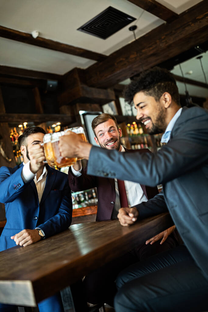 Vrolijke oude vrienden, zakenman die plezier heeft en bier drinkt aan de bar in pub. - Foto, afbeelding