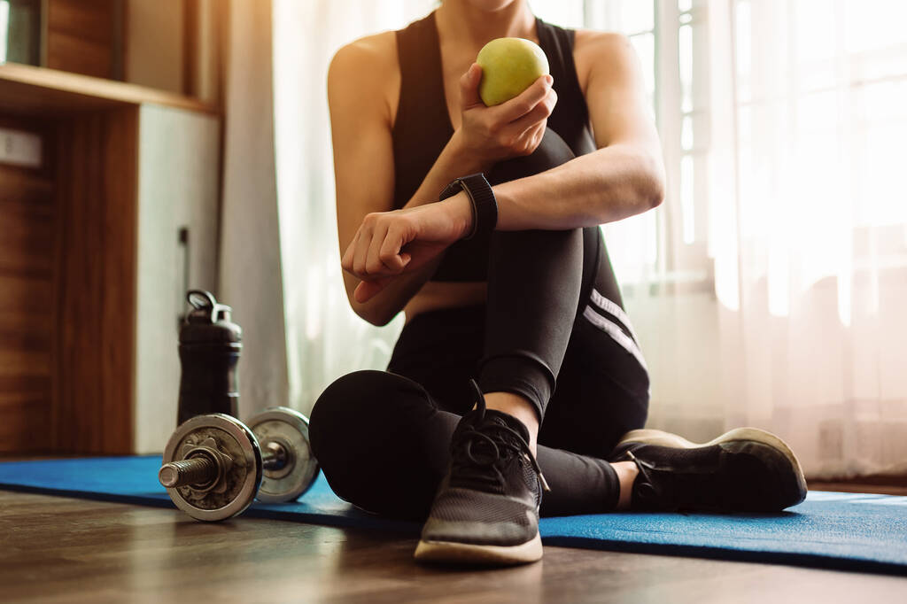 Mujer ejercitándose en el gimnasio, Mujer joven ejercitándose en forma para su salud. Ella sostiene manzana verde. - Foto, imagen