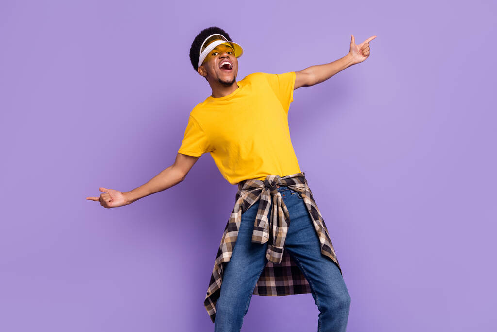 Porträt von attraktiven coolen fröhlichen Kerl mit Sonnenhut Clubbing tanzen isoliert über violett lila Farbe Hintergrund - Foto, Bild