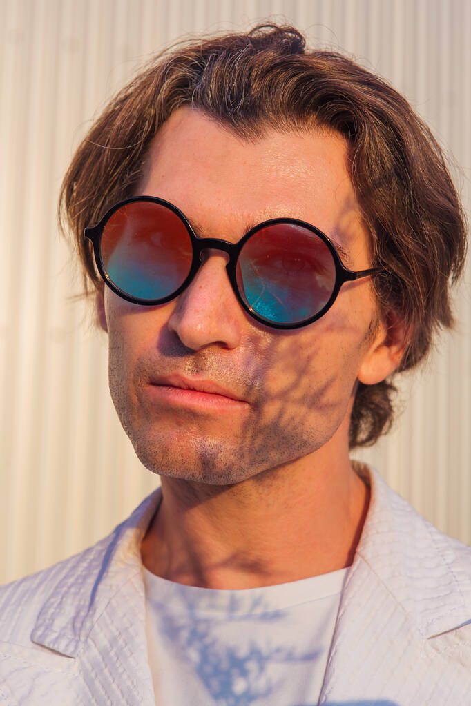 Güneş batarken yuvarlak güneş gözlüklü yakışıklı bir adamın portresi. - Fotoğraf, Görsel
