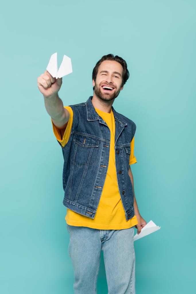 Smiling man holding paper planes isolated on blue  - Photo, Image