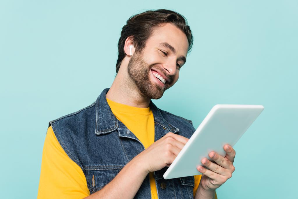 Молодий чоловік у навушниках за допомогою цифрового планшета ізольовано на синьому
  - Фото, зображення