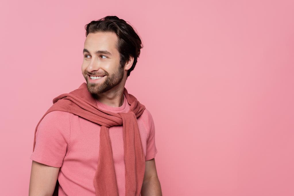 Χαρούμενος άντρας με t-shirt κοιτάζει μακριά απομονωμένος στο ροζ - Φωτογραφία, εικόνα