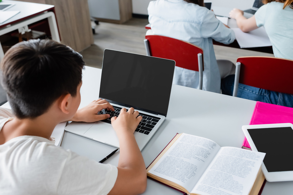 Overhead-Ansicht von Schüler mit Laptop mit leerem Bildschirm in der Nähe von Buch  - Foto, Bild