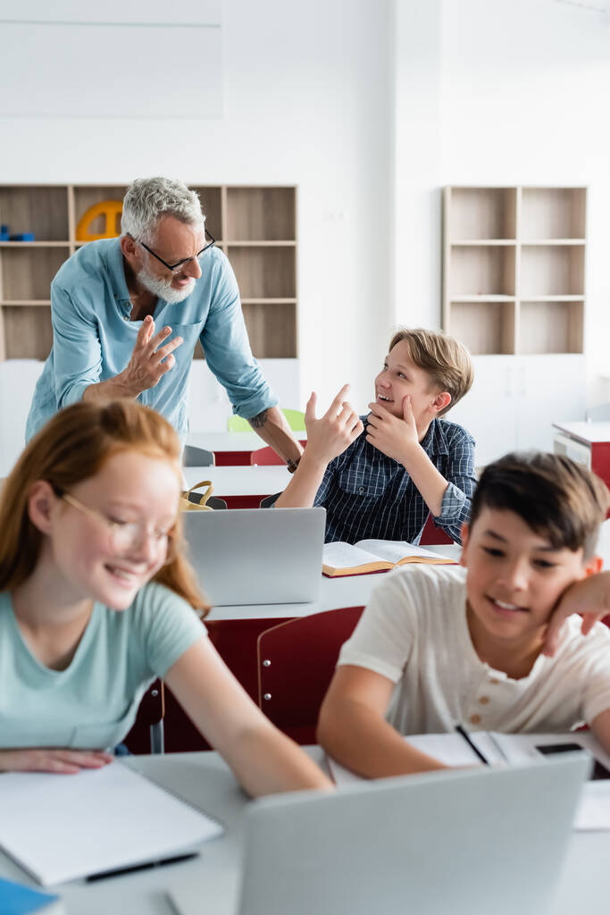 Веселий вчитель і школяр розмовляє поблизу багатоетнічних однокласників
  - Фото, зображення