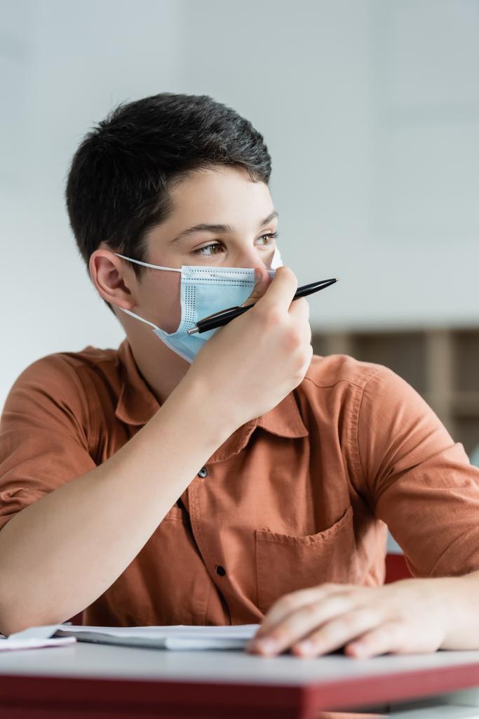 Schoolboy holding pen and wearing medical mask  - Photo, Image