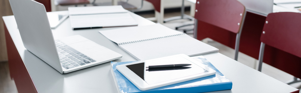 digitální tablet a notebook v blízkosti notebooků na stole v moderní škole, banner - Fotografie, Obrázek