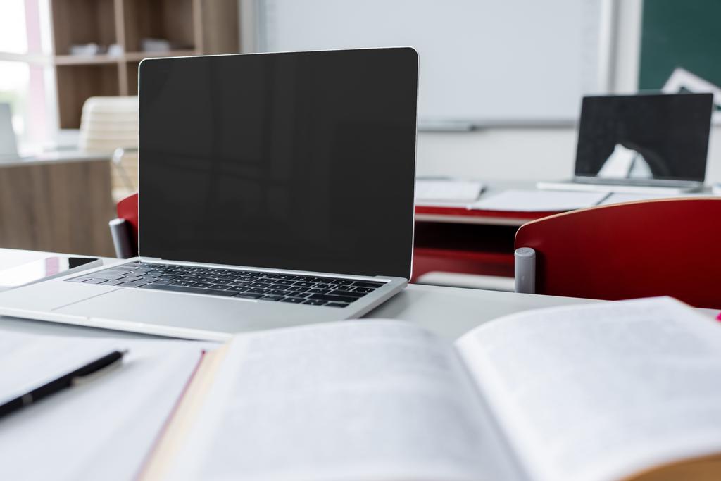 сучасний ноутбук з порожнім екраном біля розмитого підручника на шкільному столі
 - Фото, зображення
