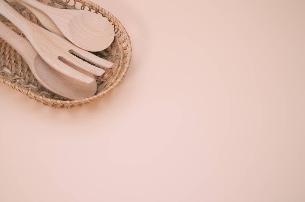 Um tiro de close-up de colheres de madeira e garfo em uma cesta tecida isolada no fundo rosa - Foto, Imagem