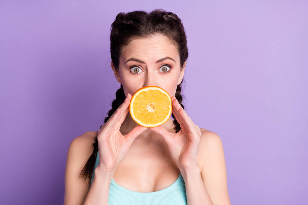 Portrait of attractive funny girlish girl closing mouth orange juicy piece isolated over violet purple color background - Foto, imagen
