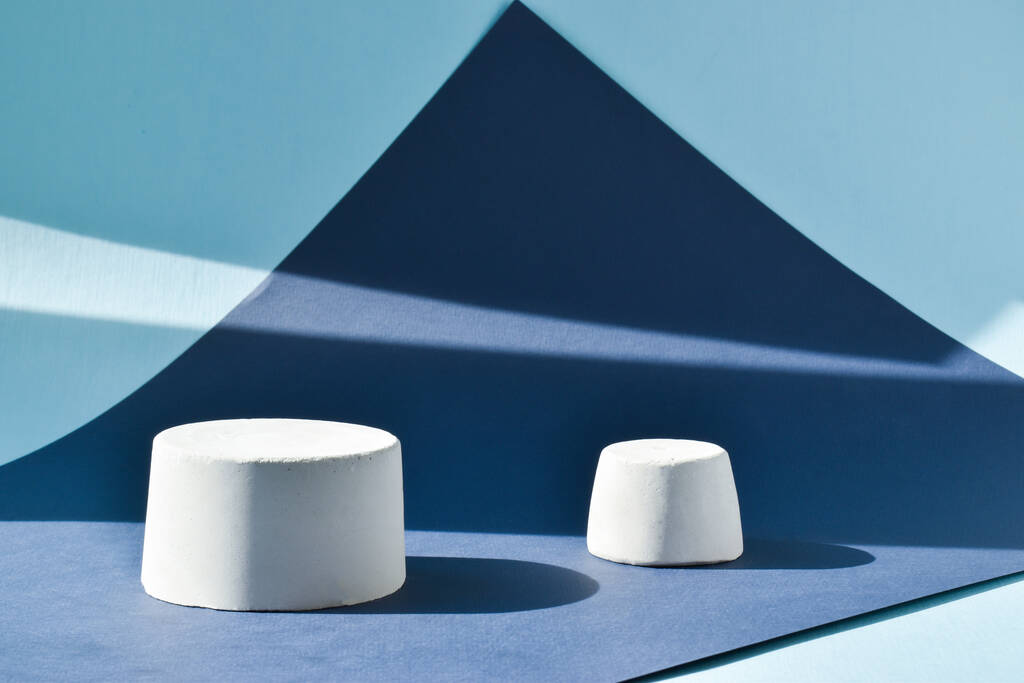 The podium is a blue background with a geometric figure made of concrete. A scene with a showcase made of cement. Minimalistic background. Presentation of cosmetics. - Photo, Image