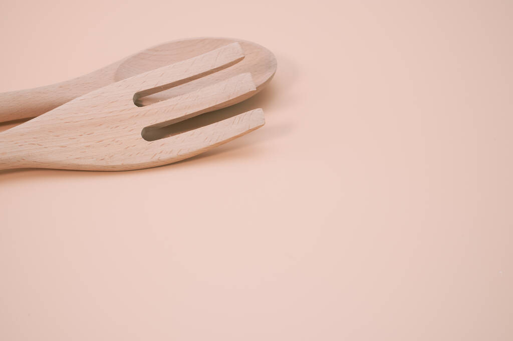 Um tiro clsoeup de um garfo de madeira e colher isolado em um fundo rosa com copyspace - Foto, Imagem