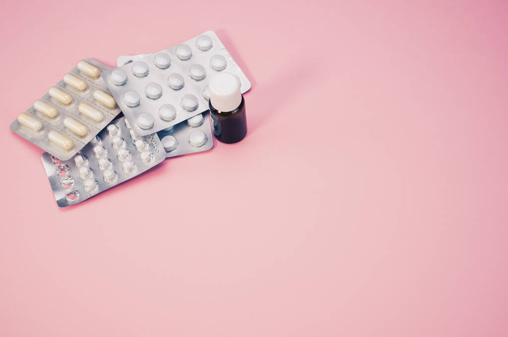 Een close-up shot van medicijn en capsule in blister geïsoleerd op een roze achtergrond - Foto, afbeelding