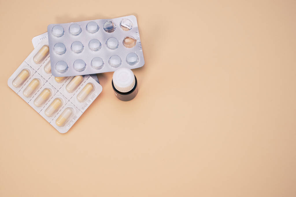 Вид сверху на бутылку с лекарствами и таблетки изолированы на светло-коричневом фоне с копировальным пространством - Фото, изображение