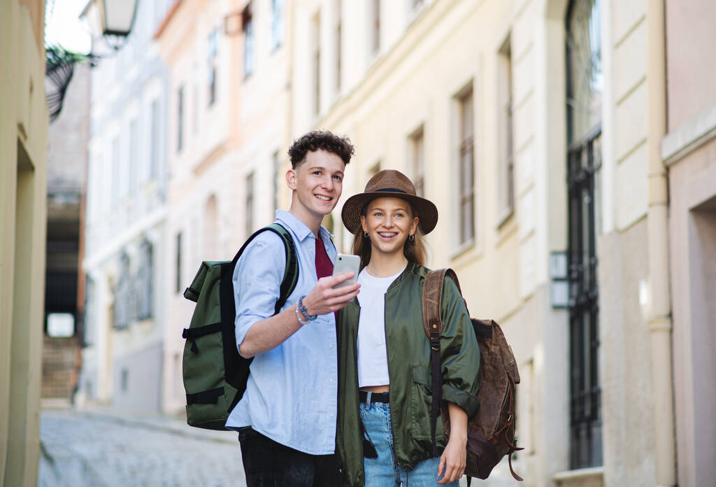 Jóvenes viajeros en pareja utilizando el teléfono inteligente en la ciudad de vacaciones, turismo. - Foto, imagen