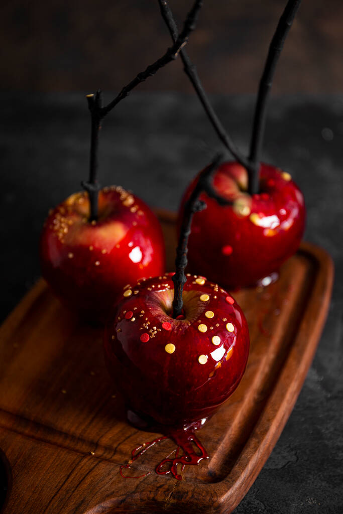 Red apples in caramel with sugar decor, an original treat for a festive Halloween table, vertical photo - Photo, Image