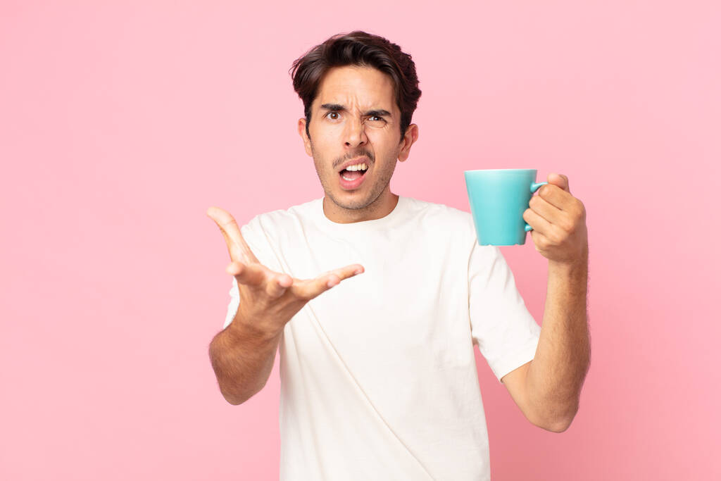 junger hispanischer Mann, der wütend, genervt und frustriert aussieht und eine Kaffeetasse in der Hand hält - Foto, Bild