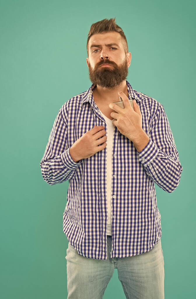 χαρισματικός γενειοφόρος άνδρας σε casual καρό πουκάμισο κρατήσει αρσενικό μπουκάλι άρωμα, άρωμα. - Φωτογραφία, εικόνα