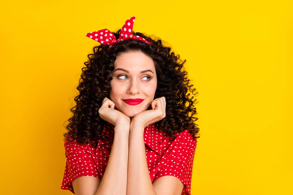 Portrait of nice optimistic brunette curly hair lady look empty space hands chin wear red band shirt isolated on yellow background - Photo, Image