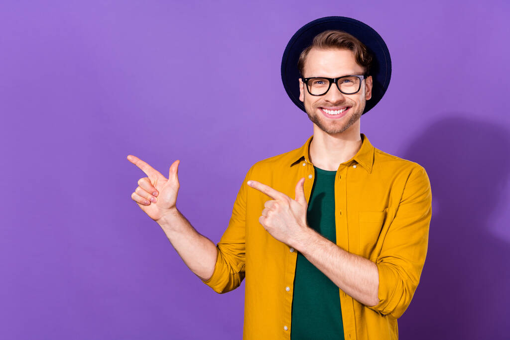 Photo of cheerful happy attractive young man point fingers empty space news isolated on violet color background - Photo, Image